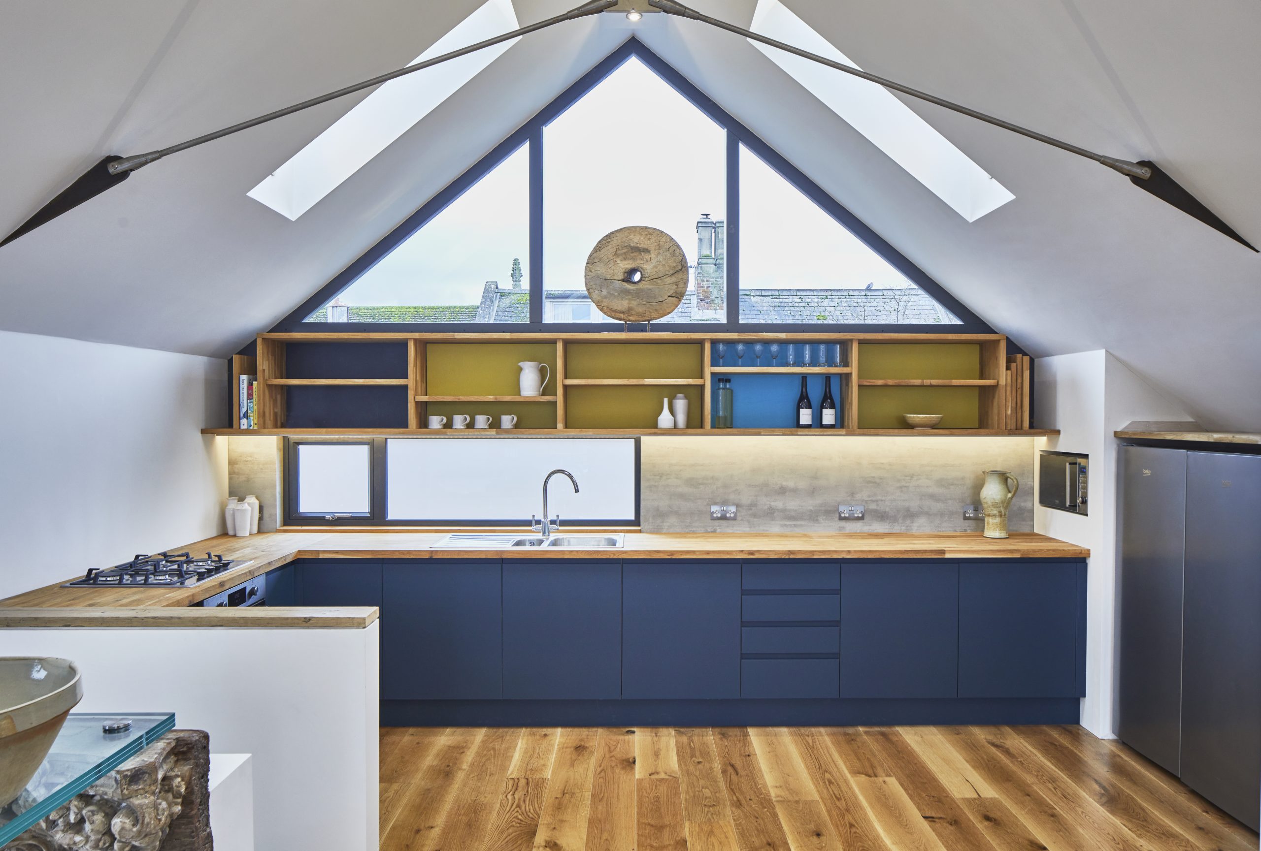 A kitchen area in a loft apartment. A modern kitchen with open shelving and wood flooring