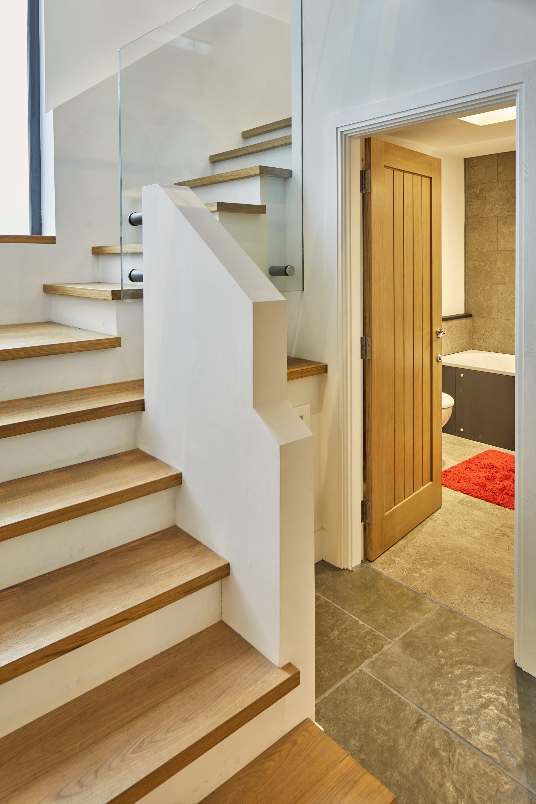 modern staircase with a view into the bathroom with a stone floor